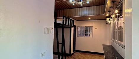 A room with wooden flooring, a bunk bed, and a window with blinds.