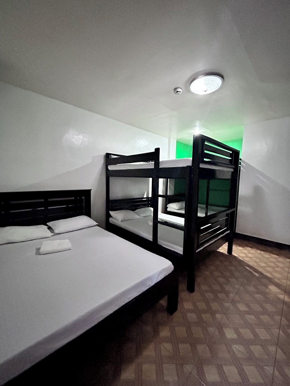 Una habitación con literas, una cama individual y una lámpara en el techo.