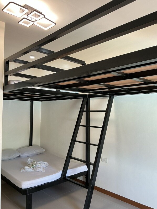 Una cama litera con escalera, colchón blanco y almohada.
