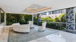 Un interior moderno con un sofá blanco curvo, una mesa de centro redonda y una alfombra estampada.