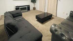 A living room with a sectional sofa, a coffee table, a TV, and a fireplace. - Spacious2 - bedroom condo in tranquil (Reynoldsburg)