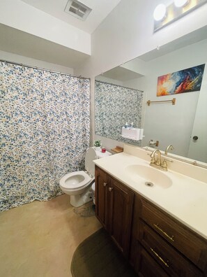 Een badkamer met toilet, wastafel en douchegordijn.