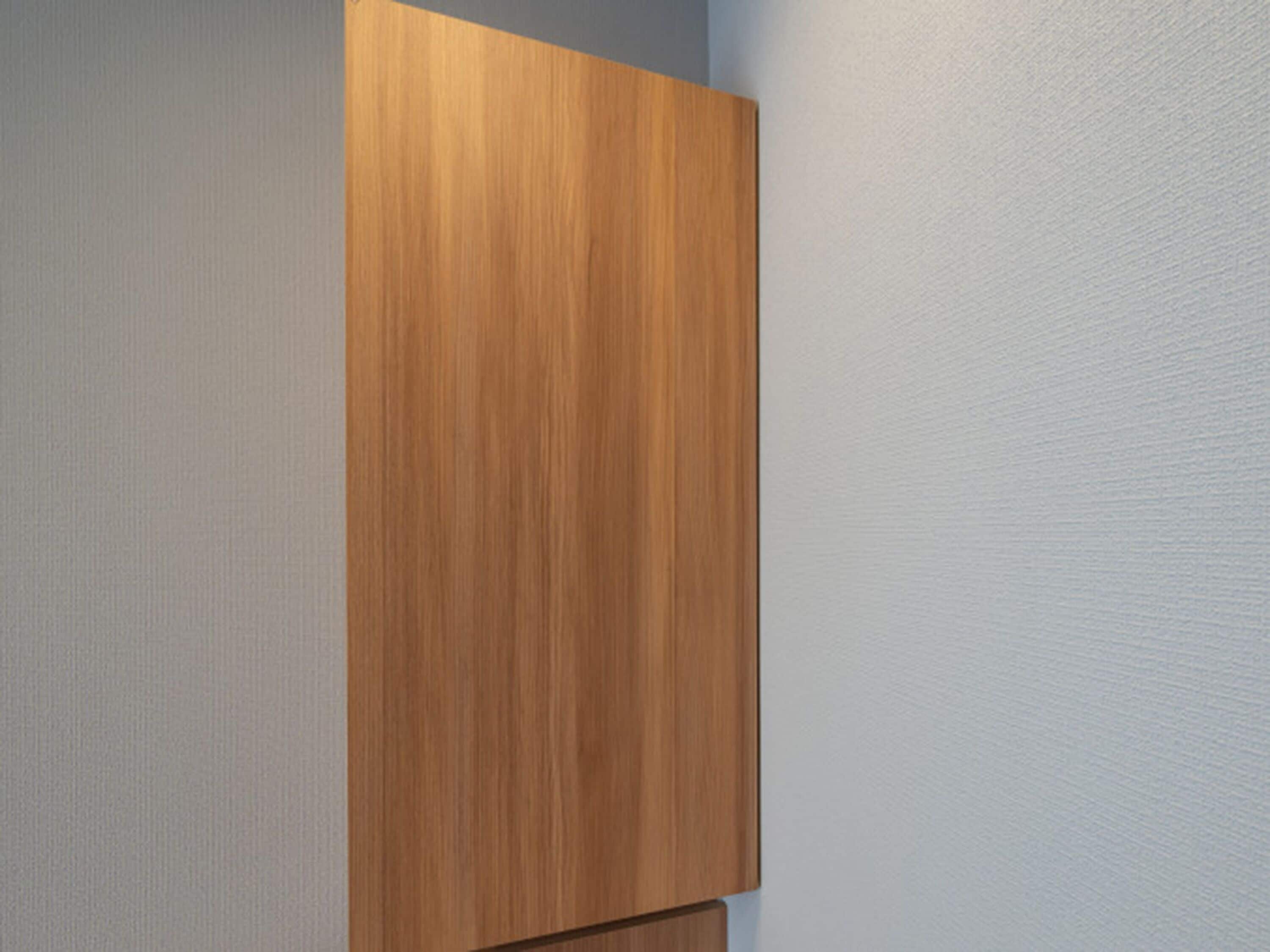 A wooden wardrobe against a textured wall.