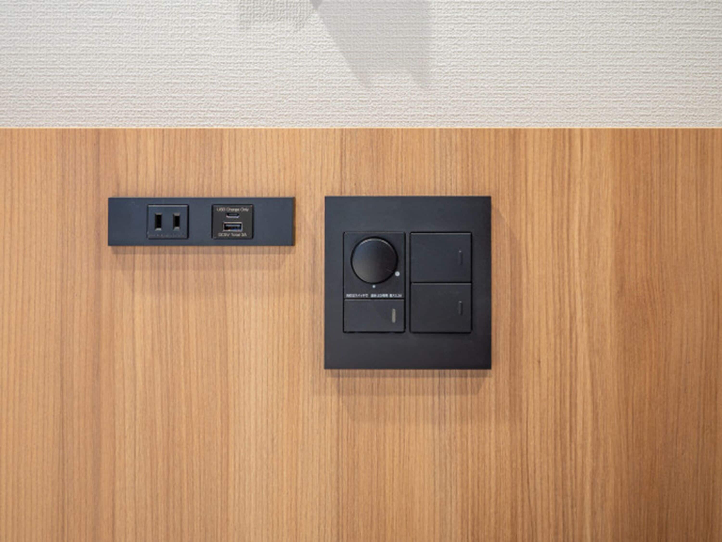 Un panel de control montado en la pared con un dial circular y dos botones, y una estación de carga USB con puerto USB tipo C.