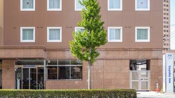 A hotel with a brown facade, multiple windows, and a tree in front.