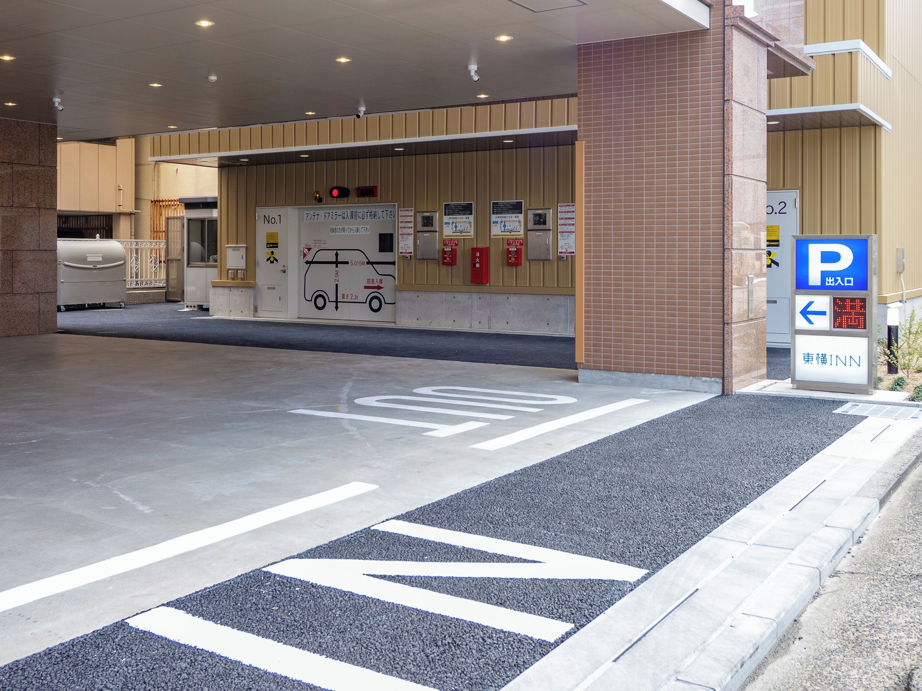 Entrada de un hotel con un letrero de estacionamiento, un extintor y una cámara de seguridad.