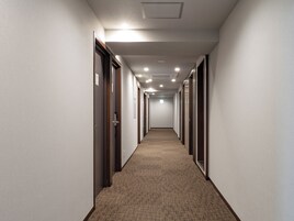 Un pasillo largo y estrecho en un hotel, con pisos alfombrados y puertas a ambos lados.
