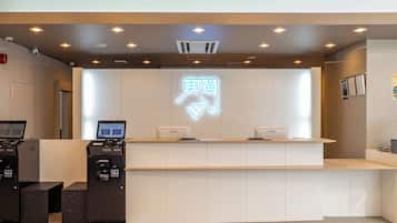 A reception desk with a digital display, a neon sign, and a printer.