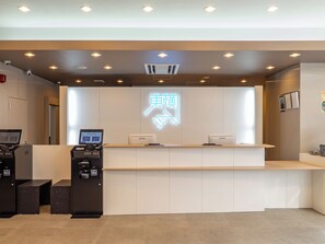 Una recepción con un panel digital, un letrero de neón e impresora.