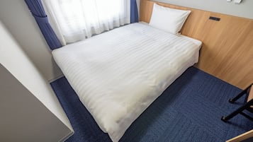 A hotel room with a bed, a wooden headboard, a blue carpet, and a window with curtains.