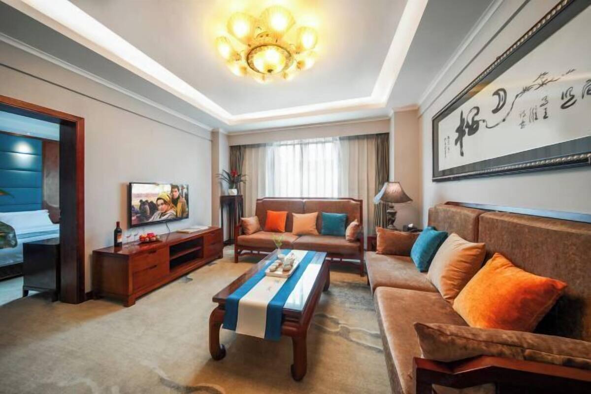 A living room with a sofa, coffee table, TV, and artwork on the wall.
