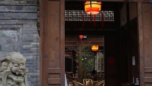 A traditional wooden entrance with a lion statue, a hanging lantern, and a sign with Chinese characters. - Lotus Hotel (Chengdu Kuanzhai Alley People's Park) (Chengdu)