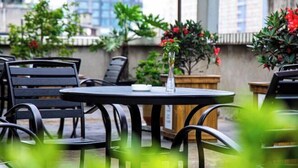 An outdoor seating area with round tables and black metal chairs, surrounded by potted plants and flowers. - Lotus Hotel (Chengdu Kuanzhai Alley People's Park) (Chengdu)