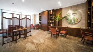 A traditional-style interior with wooden furniture, a large wall painting, and a decorative plant. - Lotus Hotel (Chengdu Kuanzhai Alley People's Park) (Chengdu)