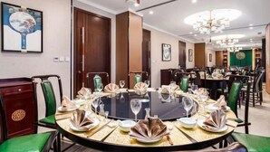 A dining area with round tables set for a meal, featuring green upholstered chairs and a chandelier overhead. - Lotus Hotel (Chengdu Kuanzhai Alley People's Park) (Chengdu)