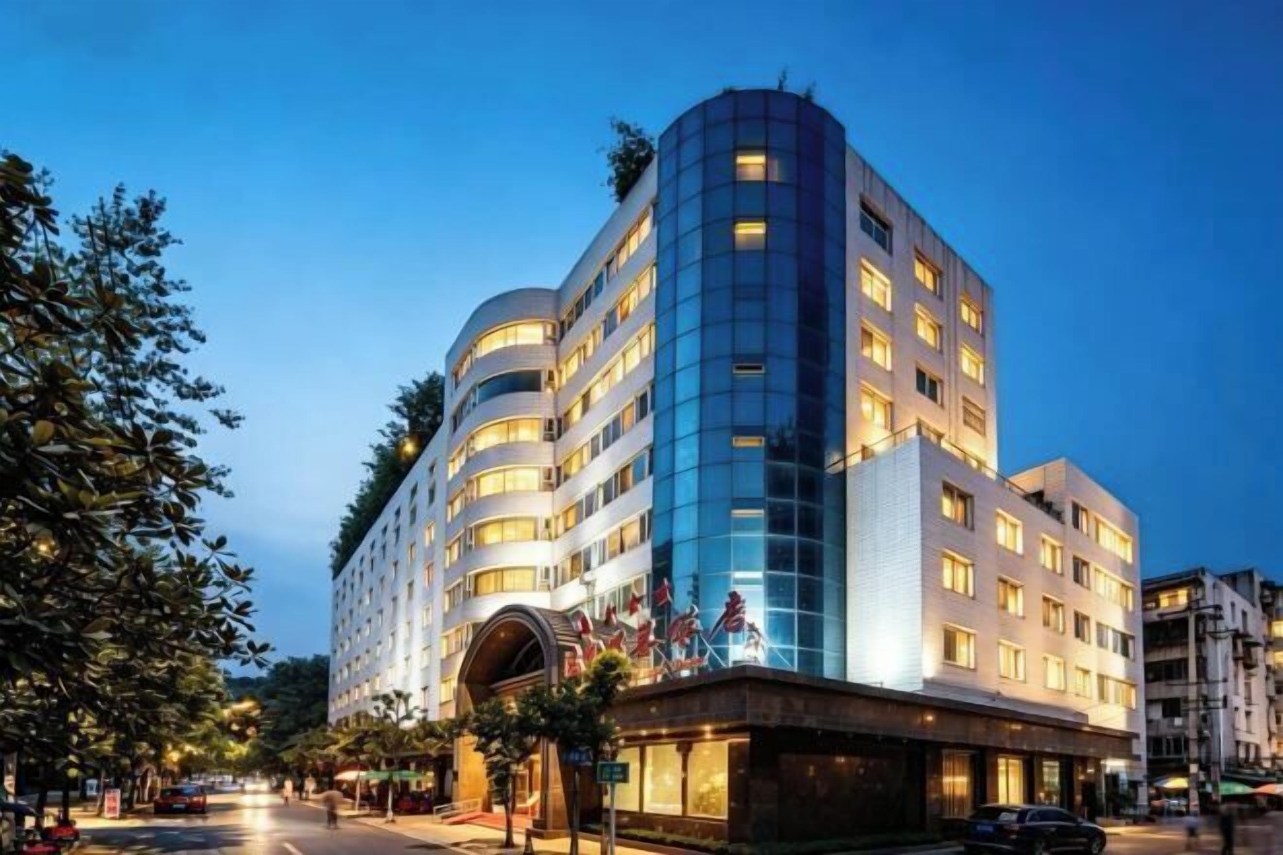 A multi-story hotel with a curved facade, a central entrance, and multiple balconies.