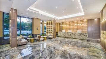 Eine Lobby mit Marmorboden, Sitzgelegenheiten, einer Rezeption und einem großen Fenster.