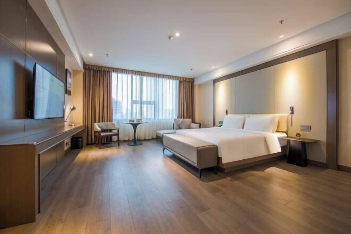 Een moderne hotelkamer met een groot bed, een bureau, een televisie en uitzicht op de stad.