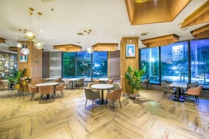Een modern interieur met ronde tafels en stoelen, grote ramen en een houten vloer.
