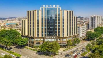 A multi-story building with a central entrance and a parking lot in front.
