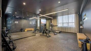 A gym with exercise equipment, a mirror, and a seating area.