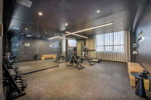 A gym with exercise equipment, a mirror, and a seating area.