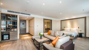 A modern hotel room with a sofa, a coffee table, a bed, and a TV. - Yangjiang Jiangcheng Junyi Square Atour X Hotel (Yangjiang)