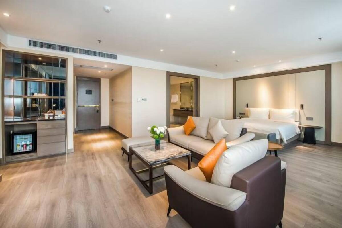 Een moderne hotelkamer met een bank, een salontafel, een bed en een televisie.