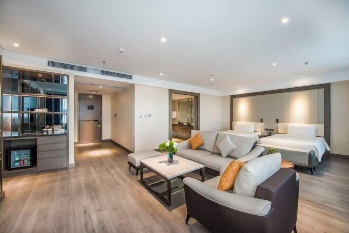 Een moderne hotelkamer met een bank, een salontafel, een bed en een kitchenette.