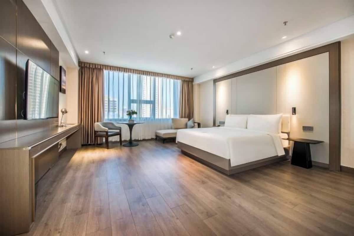 Een moderne hotelkamer met een groot bed, een bureau, een stoel en een televisie.