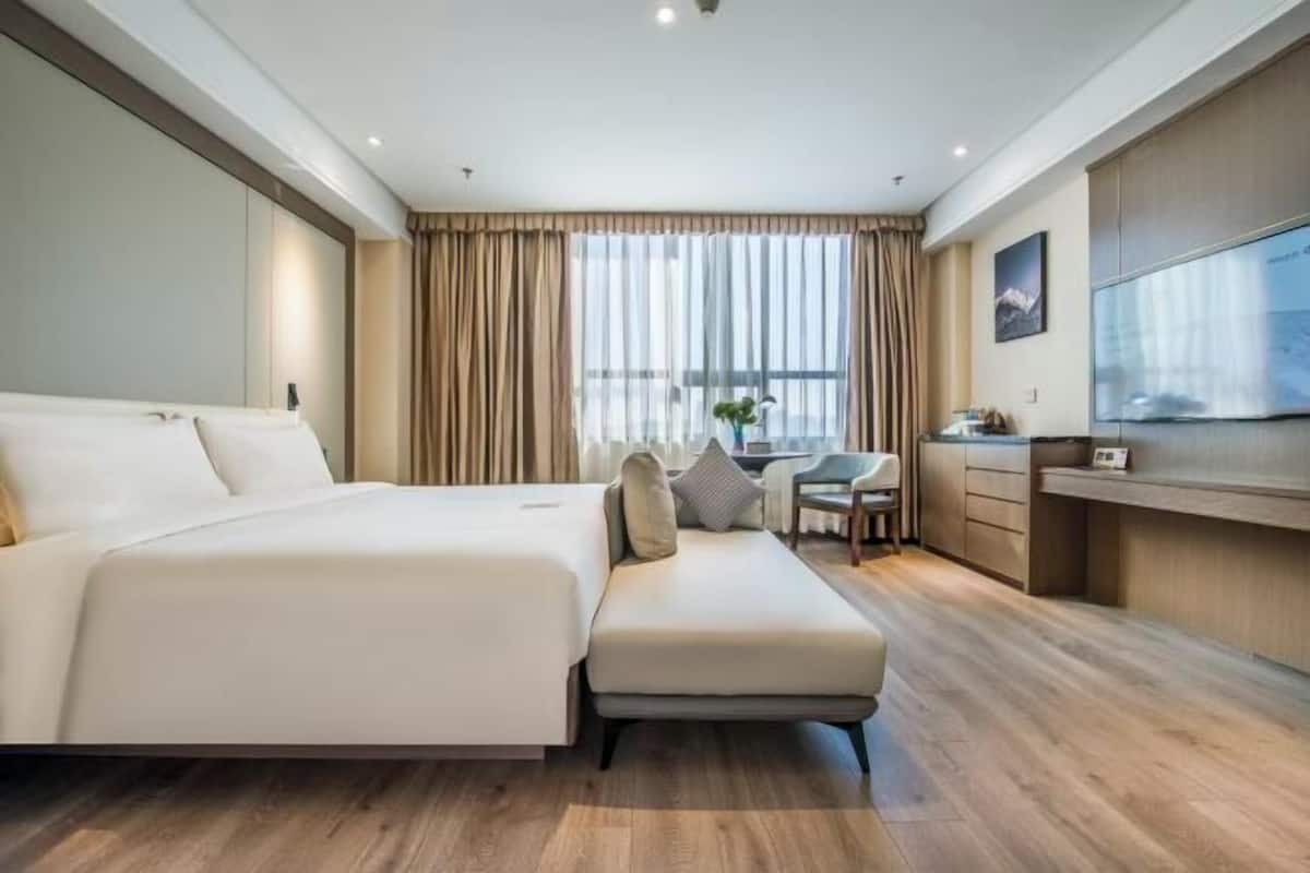 Een moderne hotelkamer met een groot bed, een bureau en een televisie.