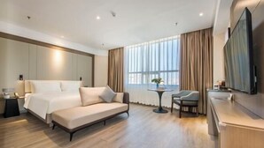 Et moderne hotelværelse med en stor seng, en sofa, et lille bord og et fjernsyn.