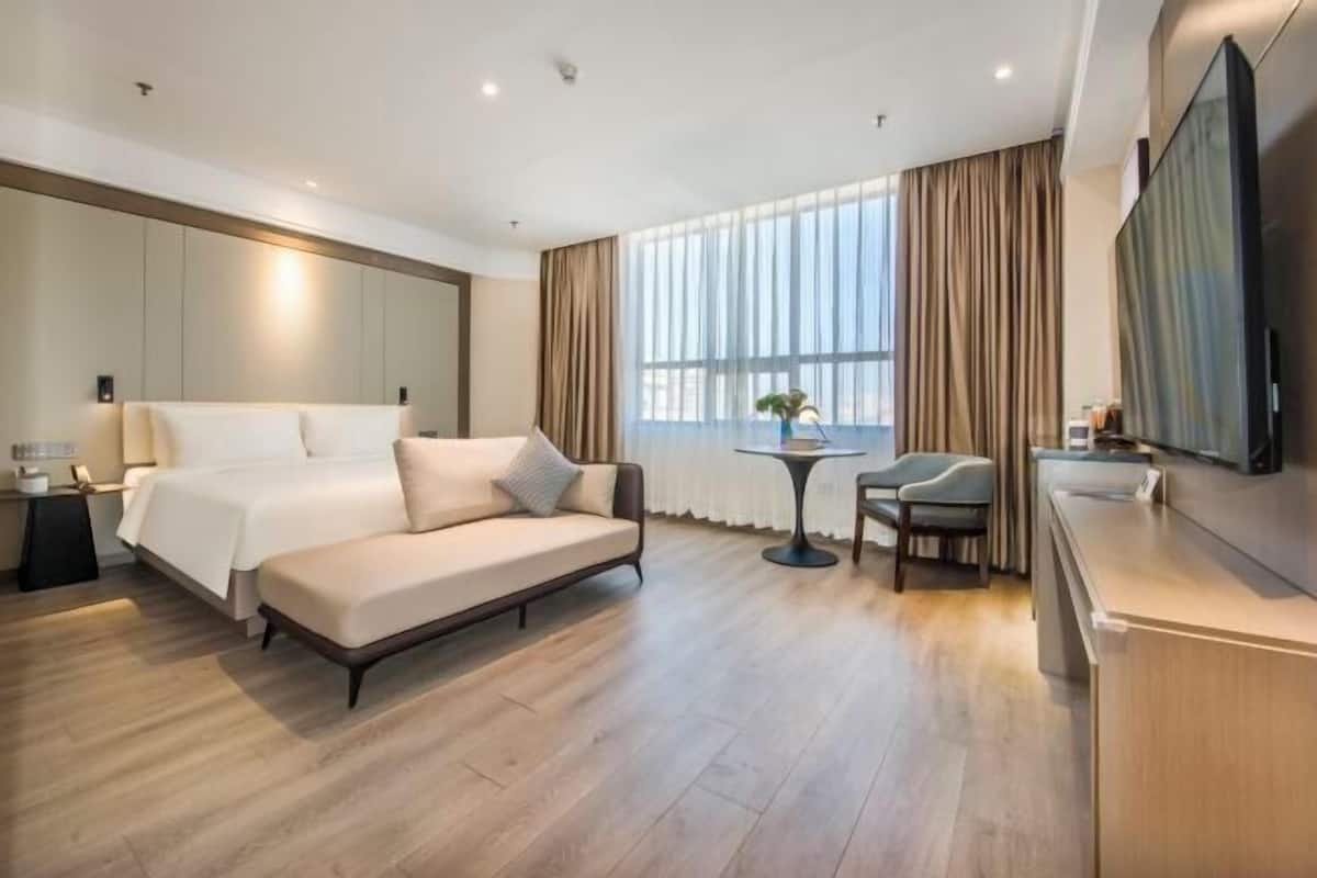 Een moderne hotelkamer met een groot bed, een bank, een tafeltje en een televisie.