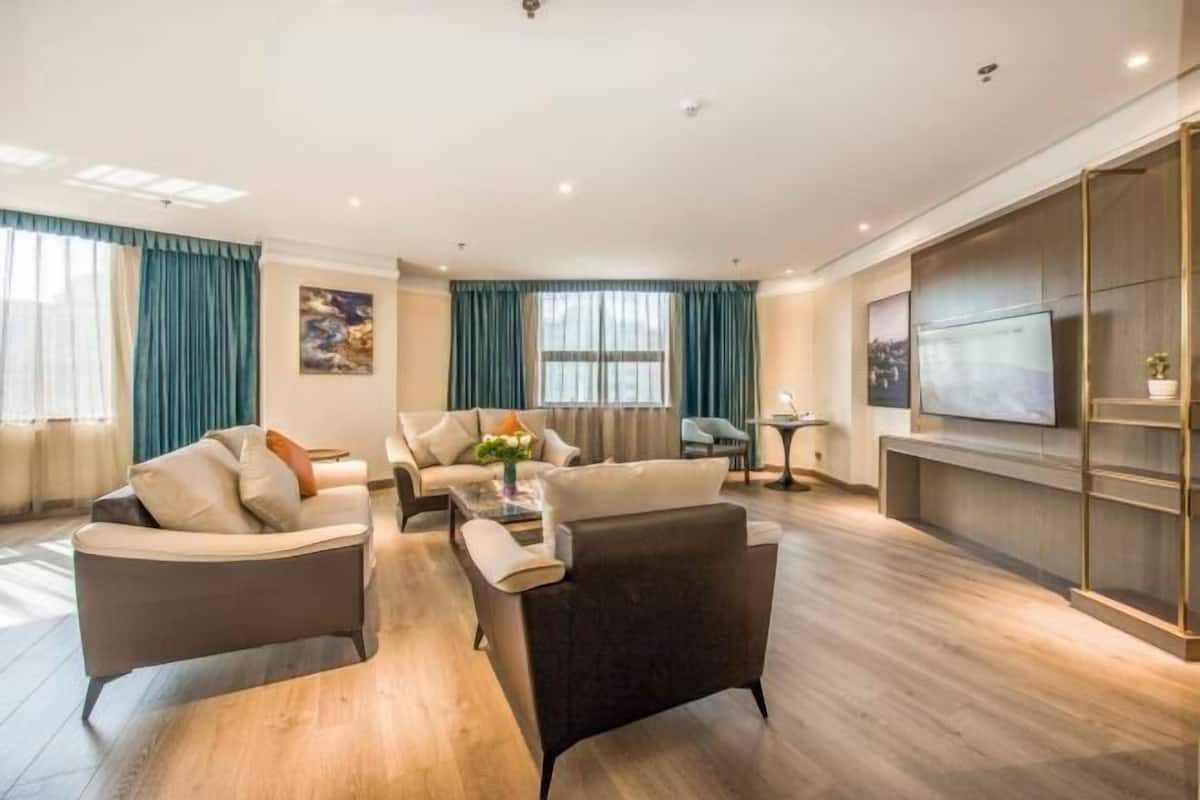Een moderne woonkamer met een zithoek, een salontafel en een aan de muur bevestigde televisie.