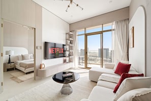 Ein modernes Wohnzimmer mit großem Flachbildfernseher, einer Couch, einem Couchtisch und einem Bücherregal.