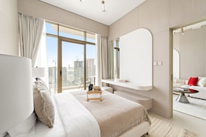Ein modernes Hotelzimmer mit einem großen Bett, einer Sitzecke, einem Schminktisch und Blick auf die Stadt.
