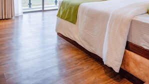 A hotel room with a large bed, a sliding glass door to a balcony, and a view of greenery outside. - Hotel Montagna  (Nuwara Eliya)