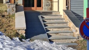Un bâtiment doté d’une façade en pierre, d’une porte d’entrée en bois et d’une rampe menant à la porte.