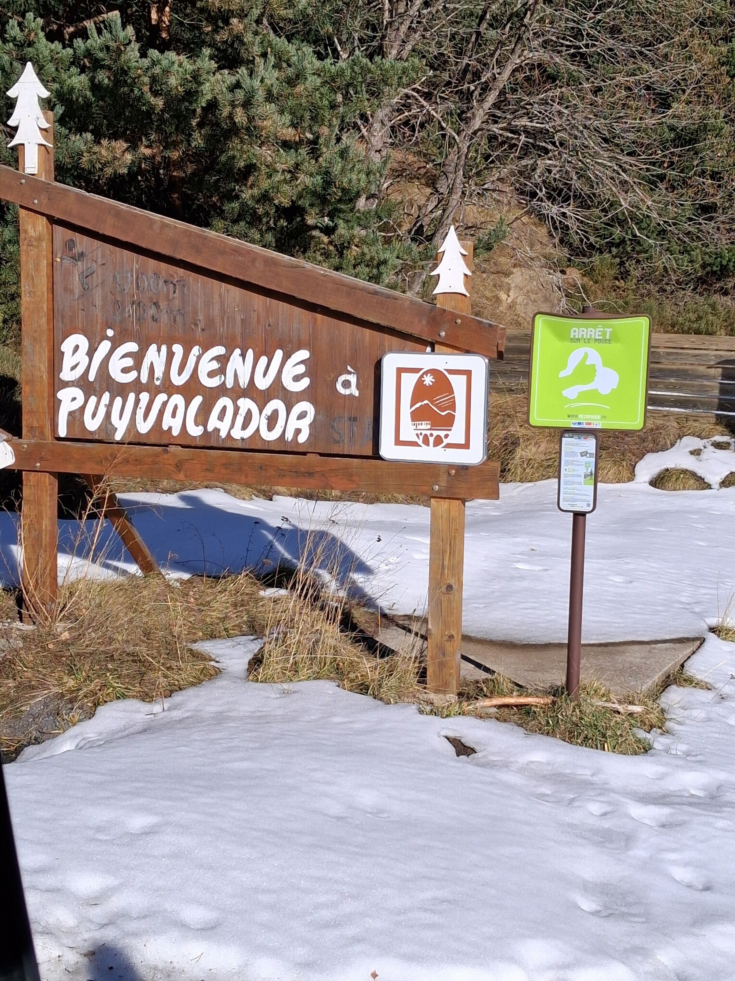 Un panneau en bois portant l’inscription « Bienvenue à Puylaval » et un symbole représentant la randonnée, indiquant ainsi l’accès à Puylaval et à une zone propice à la randonnée.
