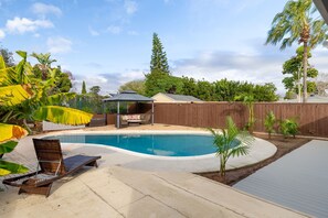 A backyard with a swimming pool, a covered seating area, and a wooden fence. - Private Pool Oasis: Modern 3BR/2BA. Sleeps 8 (San Diego)