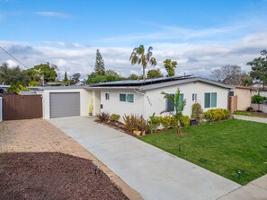 A single-story house with a garage, a well-maintained lawn, and a variety of plants. - Private Pool Oasis: Modern 3BR/2BA. Sleeps 8 (San Diego)