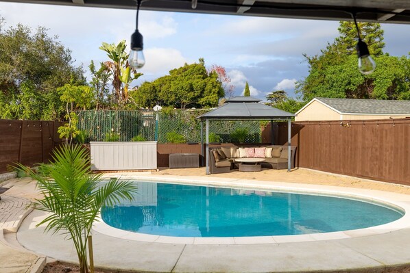 A backyard with a swimming pool, a covered seating area, and a fenced garden. - Private Pool Oasis: Modern 3BR/2BA. Sleeps 8 (San Diego)