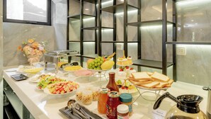A buffet with various food items, a coffee maker, and a decorative vase. - Bailey Hotel Hue (Hue)
