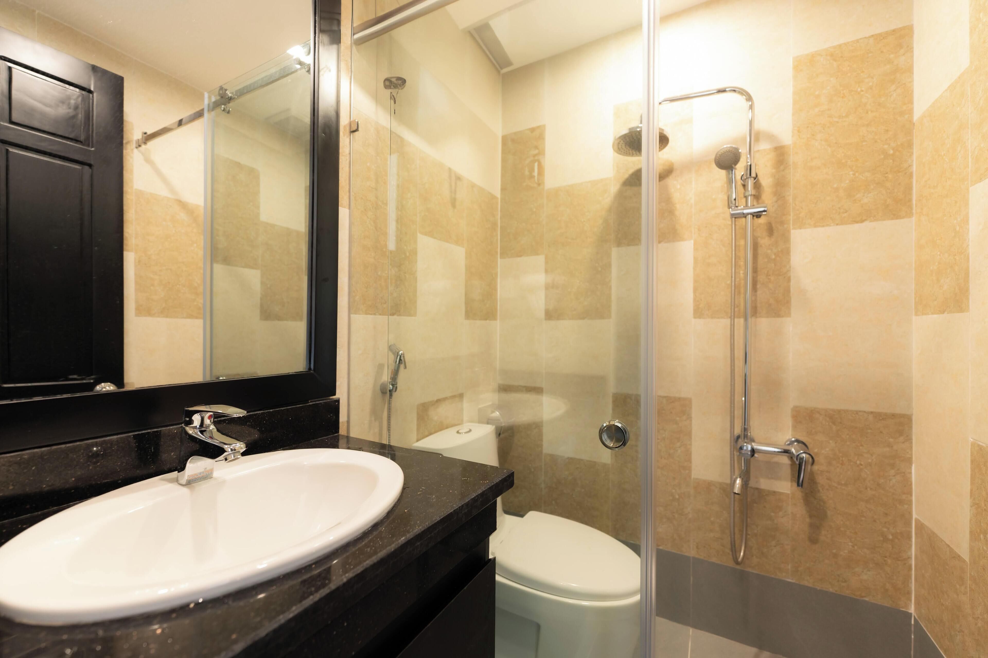 A modern bathroom with a glass-enclosed shower, a white sink, and a toilet.