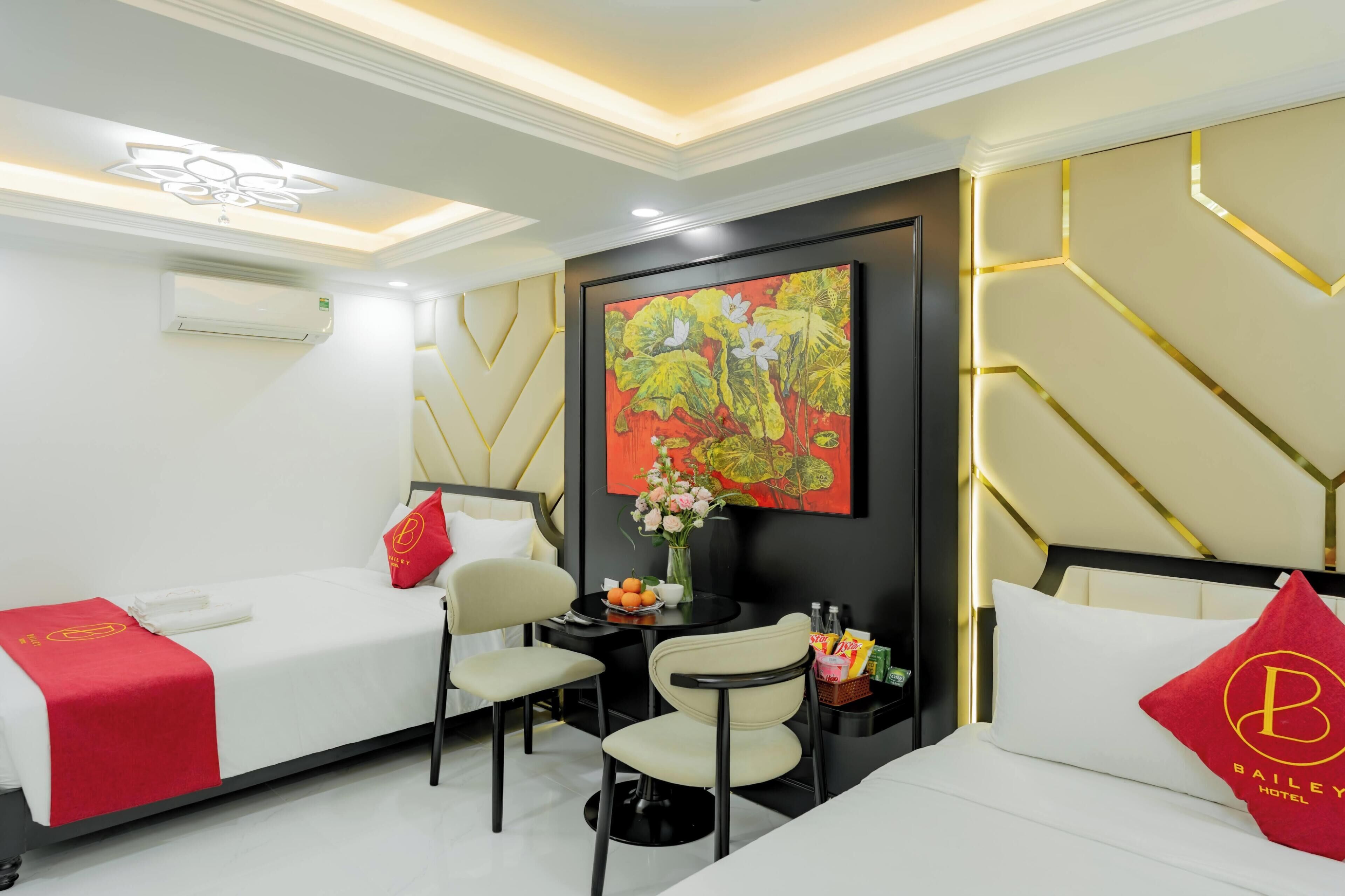 A hotel room with two beds, a small table with a vase of flowers, a chair, and a wall-mounted air conditioner.