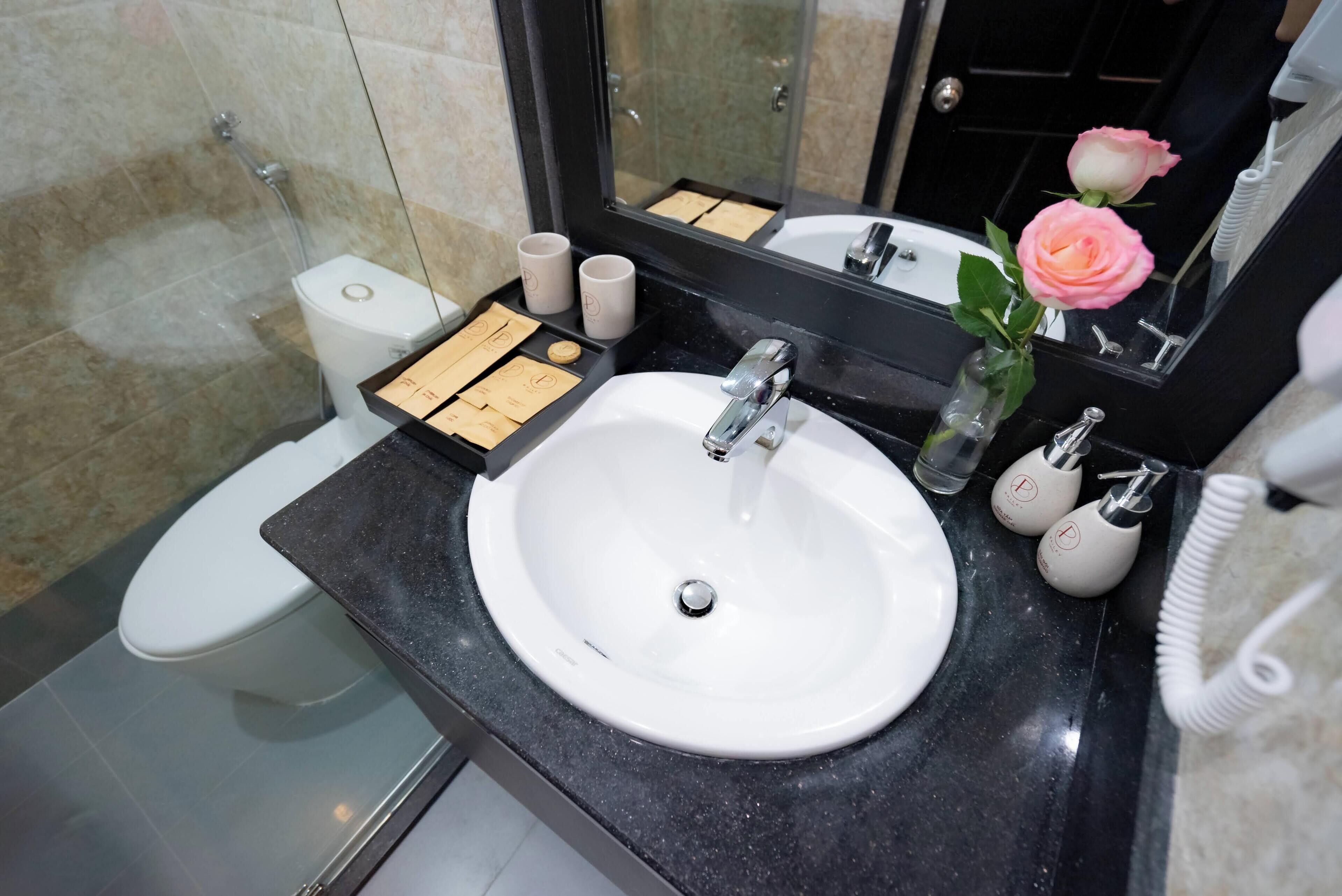 Un bagno con lavandino bianco, uno specchio, un water e una doccia.