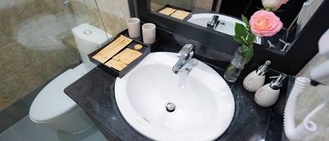 Un bagno con lavandino bianco, uno specchio, un water e una doccia.