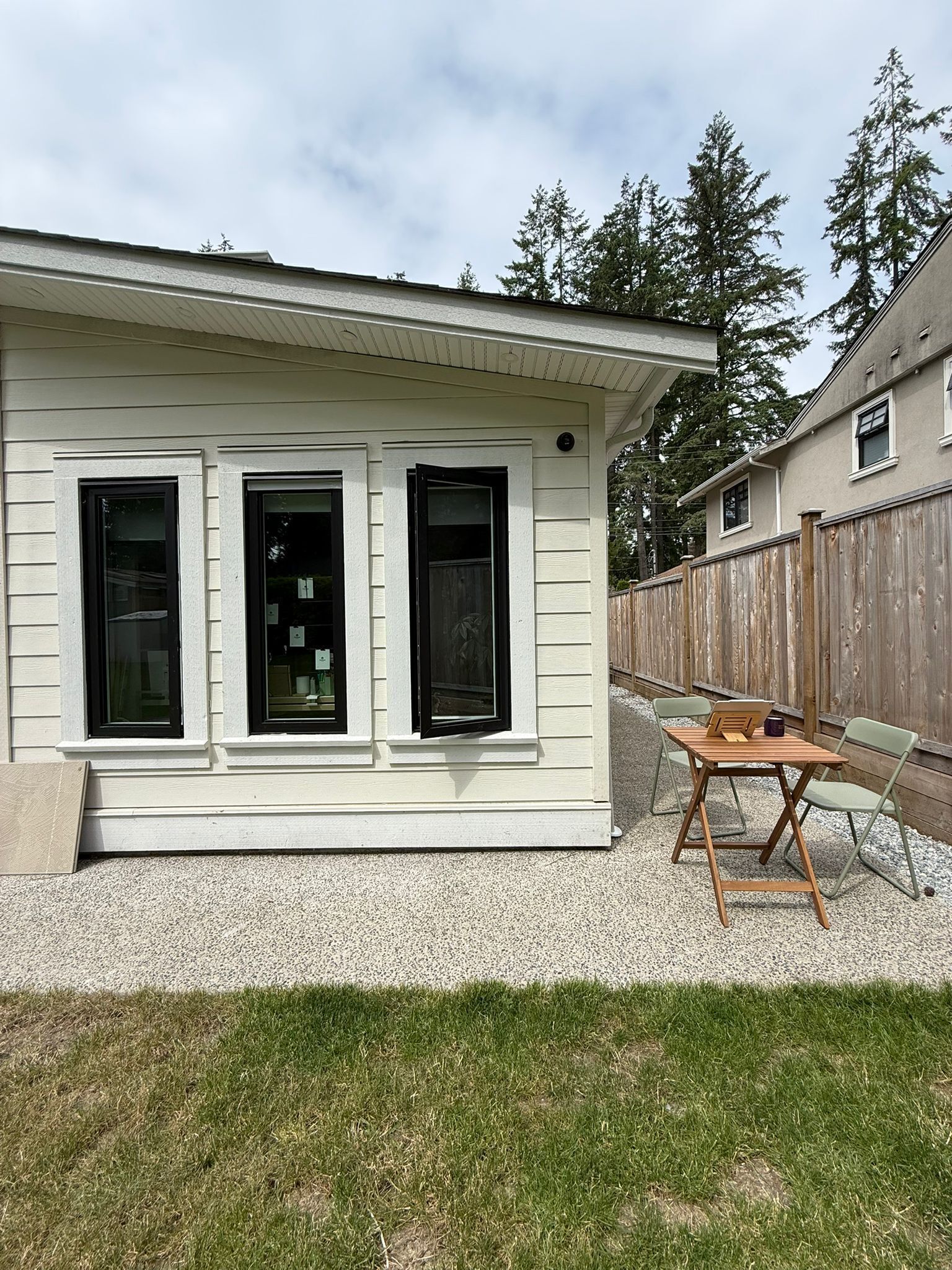 A single-story house with three windows, a wooden deck, and a wooden fence.
