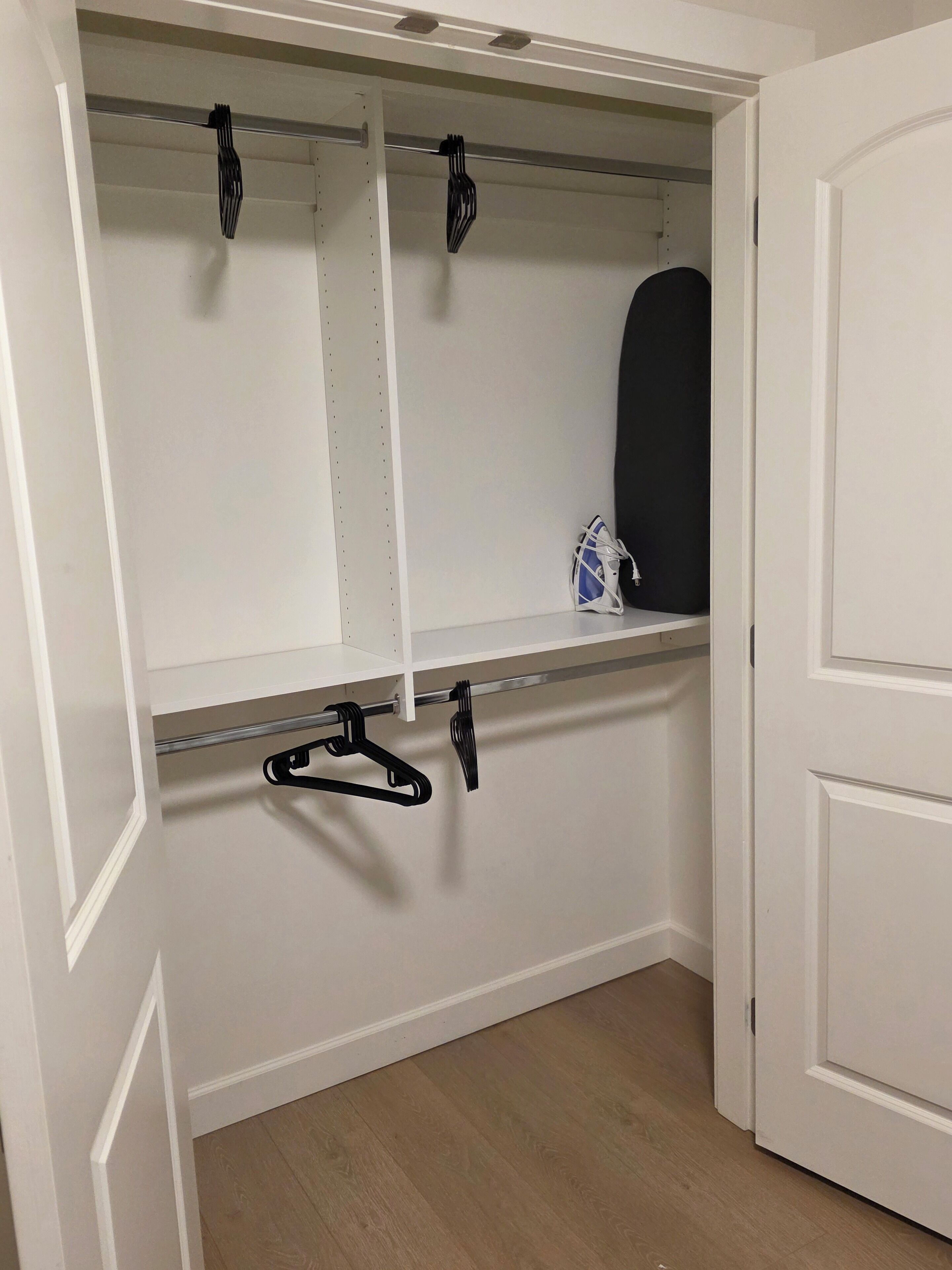 A closet with open doors, featuring multiple shelves and hanging space.