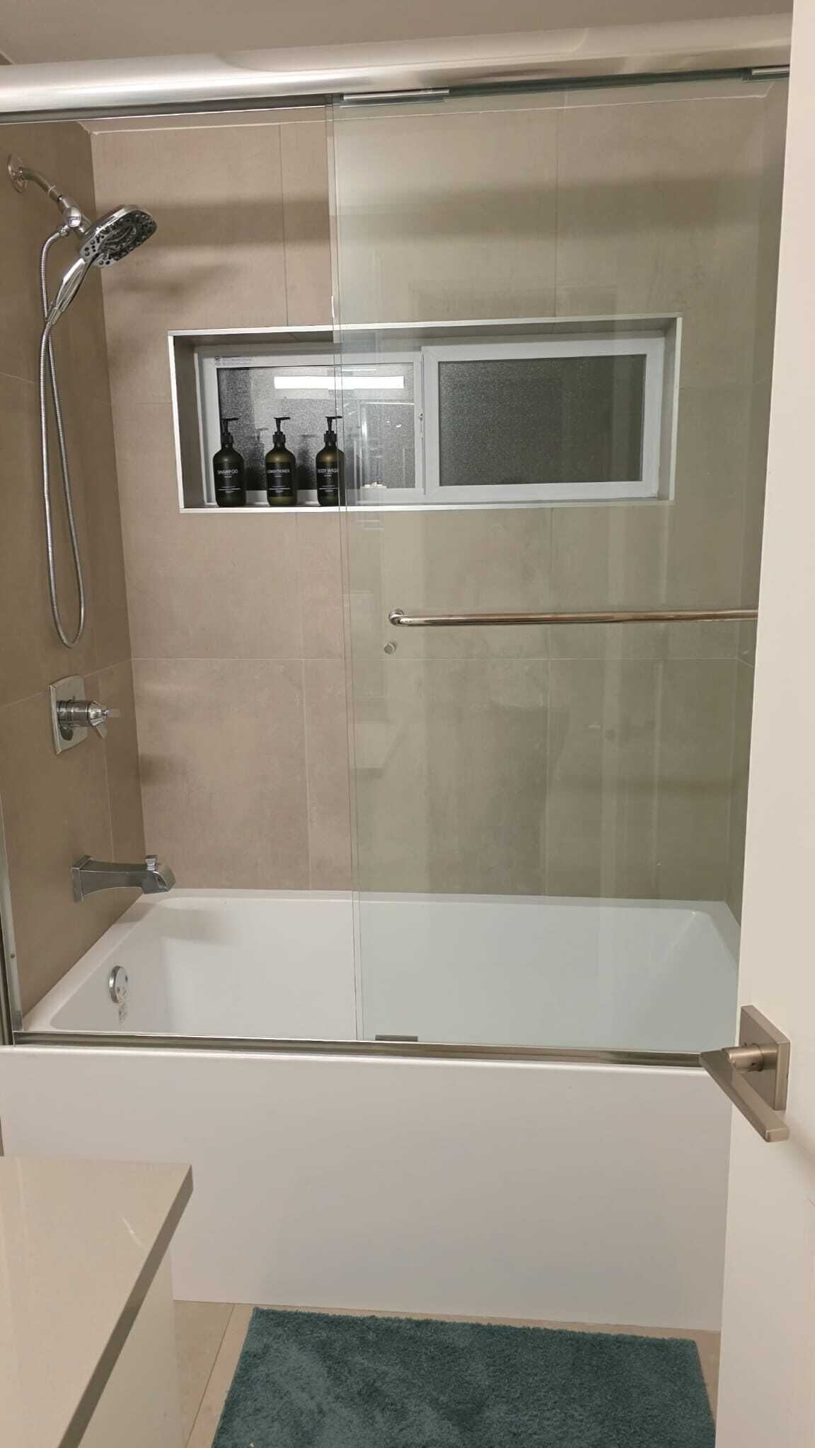 Ein modernes Badezimmer mit einer Duschkabine, einer integrierten Ablage mit Pflegeprodukten und einer Badewanne.